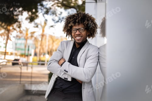 Preview: Portrait of confident black businessman posing with crossed arms by office center and smiling at