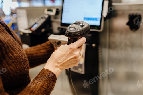 Preview: Senior woman scanning item at digital self service checkout