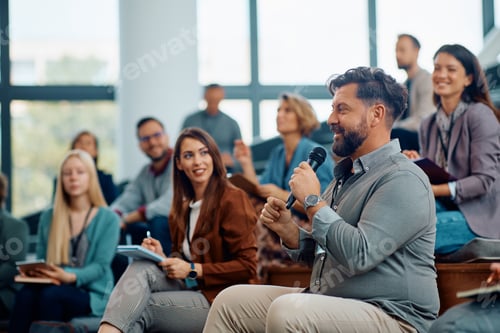Preview: Male entrepreneur asking a question while attending business seminar in conference hall.