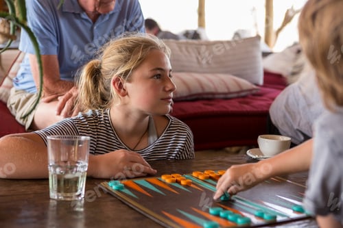 Preview: A family on vacation, people playing backgammon at a tented camp in a wildlife reserve.