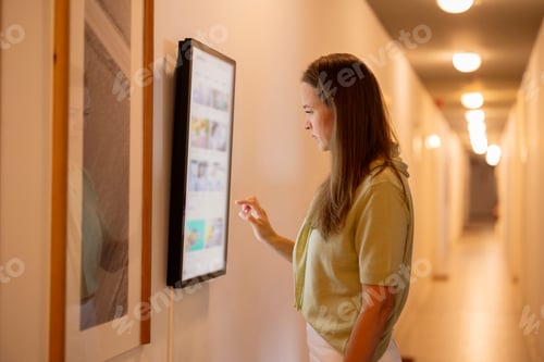 Preview: Woman interacting digital smart display in hallway