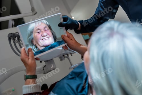 Preview: Senior woman admiring her new smile after dental treatment