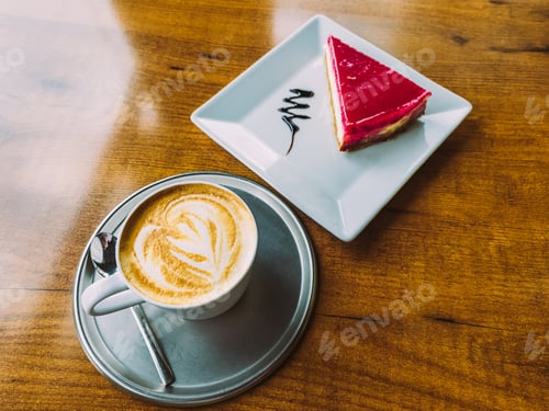 Preview: A cup of cappuccino and a piece of cheesecake on a wooden table.