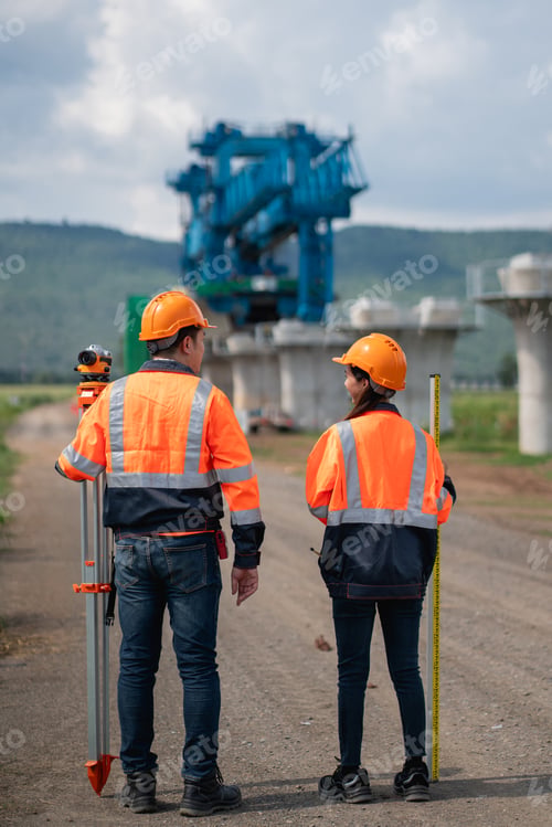 Preview: Survey team is working with a theodolite and road construction plans.