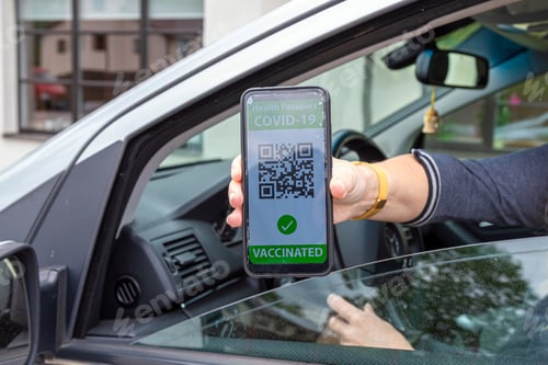 Preview: driver in car shows a digital coronavirus immunity vaccine passport, new normal travel concept