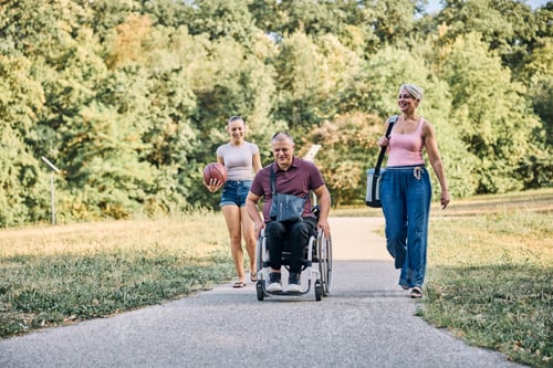 Vorschau: Familie geht mit einem Mann mit Behinderung im Park spazieren