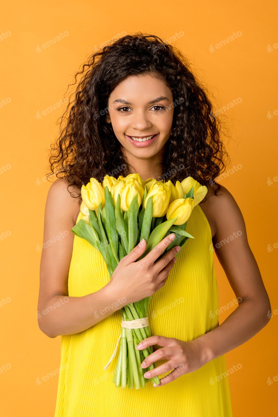 Cover for happy curly african american woman holding yellow tulips isolated on orange