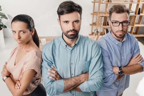 Preview: high angle view of serious business people with crossed arms standing at workplace in office