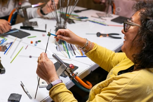 Preview: Woman learning to make handmade glass jewelry in a workshop