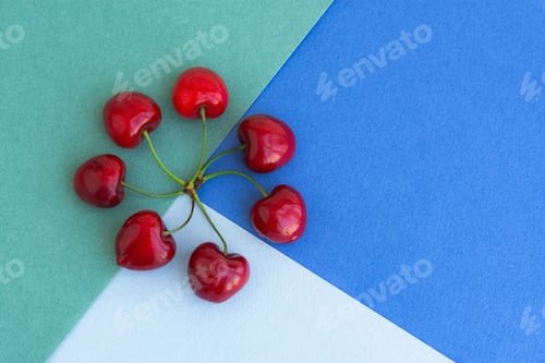 Preview: Composition of cherry berries on multicolored backgrounds top view