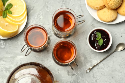 Preview: Glasses of tea in metal holders served on grey textured table, flat lay