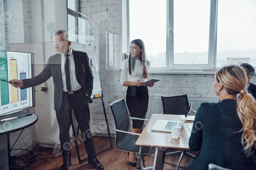 Preview: Confident businessman conducting a presentation while having staff meeting in the board room