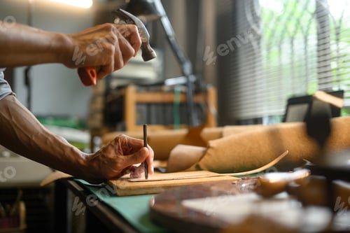 Preview: Close up shot craftsman using a hammer and other tools to shape and detail the leather piece