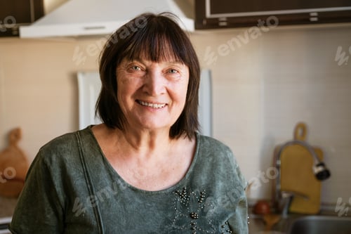 Preview: Portrait of happy senior lady sitting in kitchen at home, close-up, copy space.