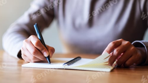Preview: Closeup image of a woman writing on a blank notebook on the table