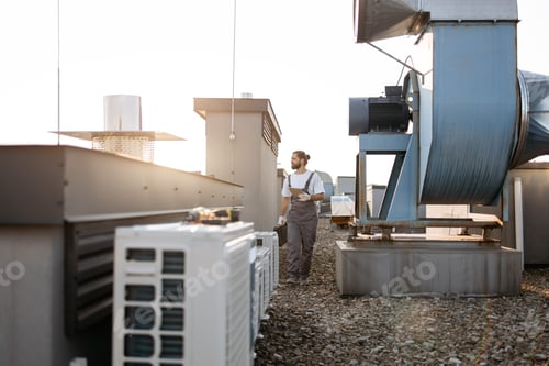 Preview: Craftsman walking by conditioners and holding tablet on roof