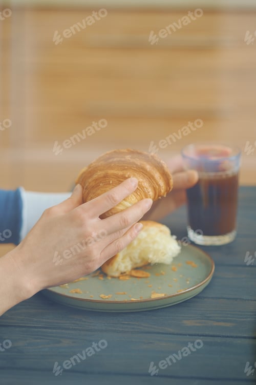 Preview: View through the window on hands of woman with croissant