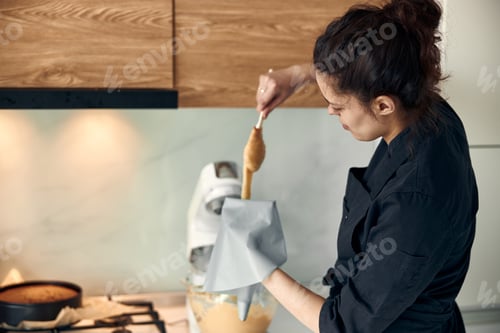 Preview: beautiful caucasian lady cook is making eclairs with help of pastry casing at home