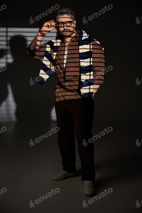 Preview: Stylish man in glasses showcases elegant fashion in creative studio setting