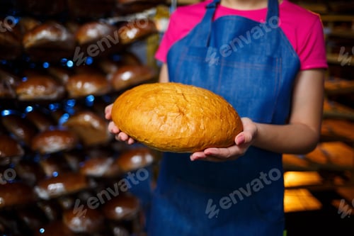 Preview: A worker works in a bakery. She puts bread on a shelf. Fresh crispy bread close-up