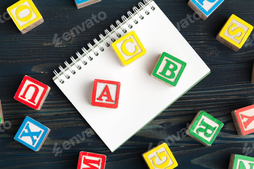 Preview: Notepad on wooden table and wood alphabet blocks