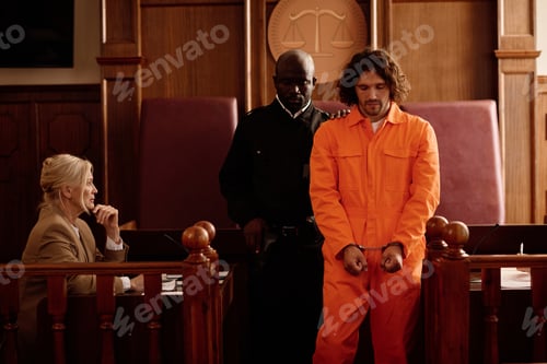 Preview: Young policeman standing next to male prisoner in cuffs and orange jumpsuit