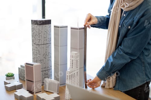 Preview: Close up of building model measured by female using ruler