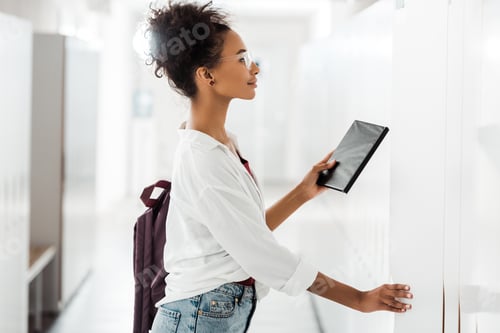 Preview: side view of african american student with notebook in corridor in university