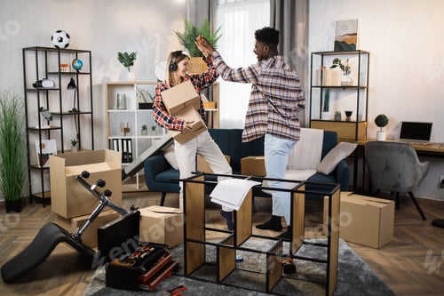 Preview: Cheerful couple giving high five at new modern house