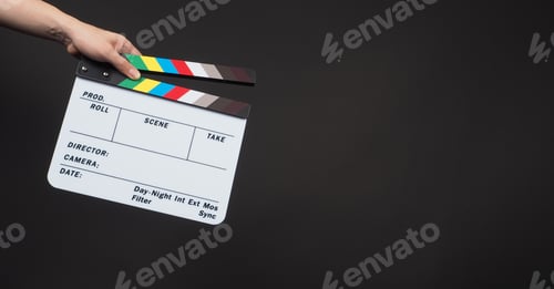 Preview: Hand is holding clapperboard or movie clapper board or slate on black background