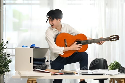 Preview: Energetic employee in white shirt with necktie around his head enjoying a music break.
