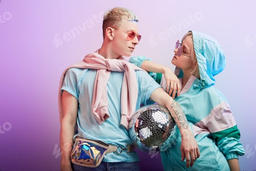 Preview: Young fashionable couple of dancers posing with disco ball on violet background