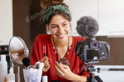 Preview: Attractive cheerful popular young woman video blogger advertising beauty products via her blog on so