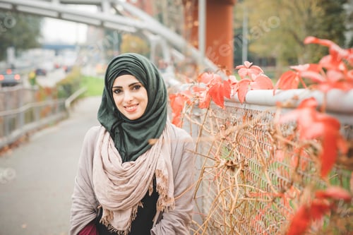 Preview: Portrait of young woman leaning against fence on park path