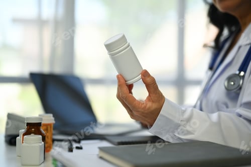 Preview: Cropped shot of mature female doctor in white uniform working at medical office