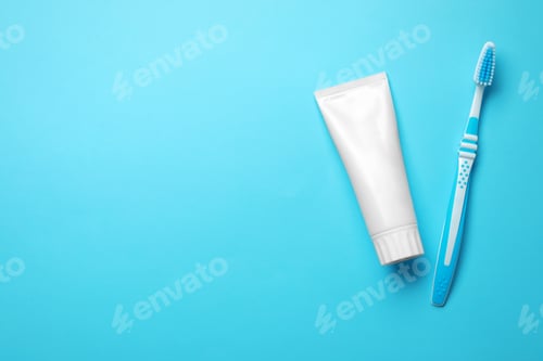 Preview: Blank tube of toothpaste and brush on color background, top view with space for text