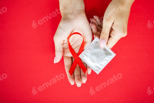 Preview: Close Up woman hand holding red ribbon HIV, world AIDS day awareness ribbon.