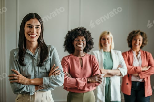 Preview: Four businesswomen smiling with arms crossed in office environment