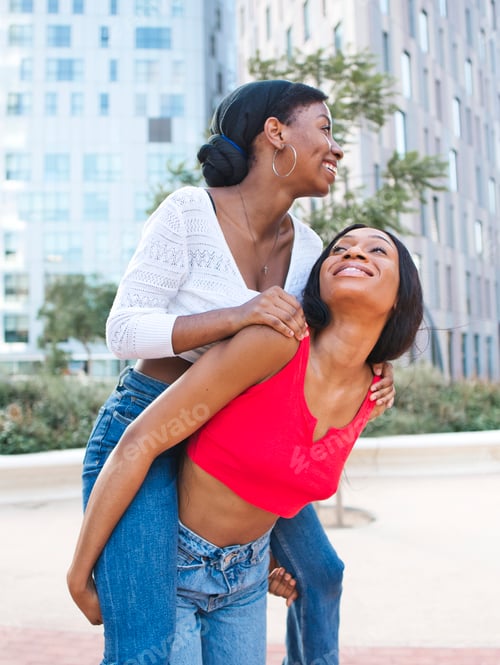 Preview: Delighted African American lesbian giving piggyback ride to content female partner while standing