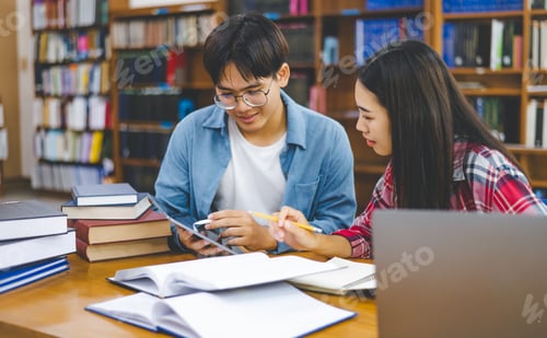 Preview: Students are consulting each other working on laptops and searching for books to study