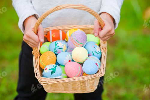 Preview: Closeup basket full of colorful Easter eggs in kids hands