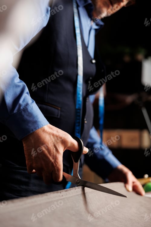 Preview: Tailor Cutting Fabric with Scissors at Workplace