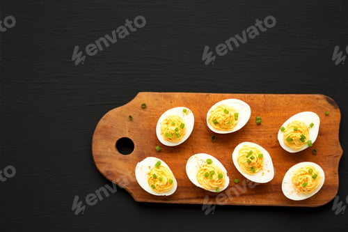 Preview: Homemade Deviled Eggs with Chives on a rustic wooden board on a black surface