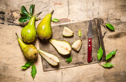 Preview: Sliced pears on old chopping board with leaves .