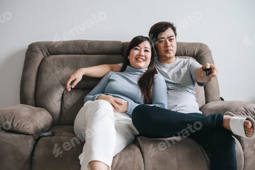 Preview: Young Asian Couple Relaxing on Sofa and Watching TV Together