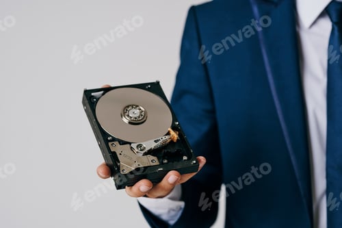 Preview: business man holding disassembled hard drive on gray background