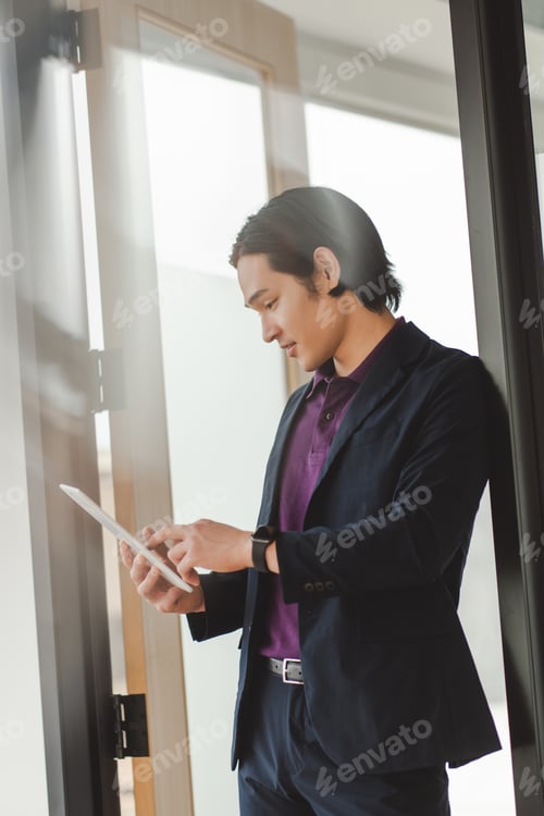Preview: Asian businessman wears black suit, using digital tablet, checks mail, working in modern office