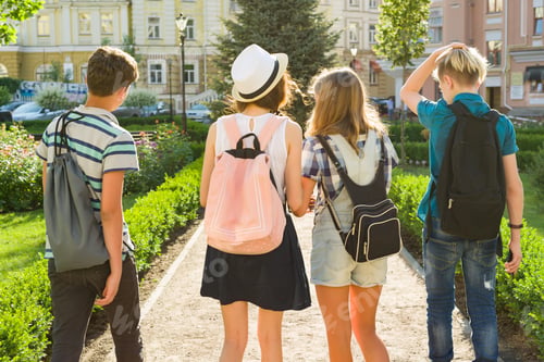 Preview: Group of happy teenagers friends 13, 14 years walking along the city street. View from the back
