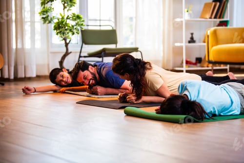 Preview: Indian young family performing plank exercise for core strength on floor at home