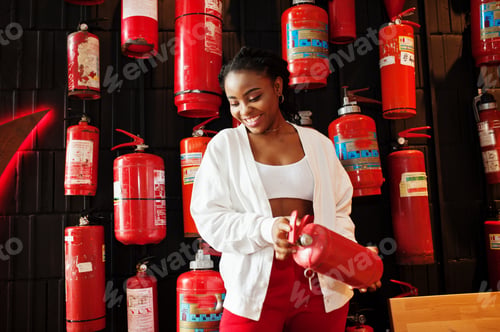 Preview: African woman posed against wall with old extinguisher.